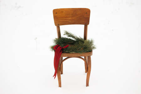Christmas wreath on rustic chair in snowy winter field. Merry Christmas! Winter holidays in countryside. Space for text. Stylish xmas wreath with pine branches and red bow hanging on wooden chairの写真素材
