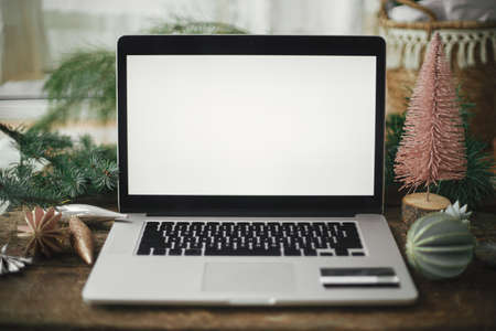 Laptop with blank screen and credit card on rustic wooden table with stylish christmas ornaments and pine tree. Christmas Sales and shopping online. Black friday and cyber monday. Space for textの写真素材