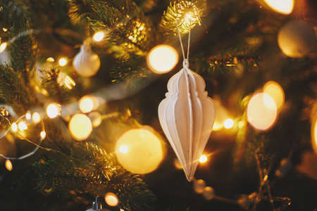 Modern christmas tree ornaments, white baubles and golden christmas lights bokeh close up. Space for text. Atmospheric festive decorated scandinavian room in night. Stylish christmas decorの写真素材