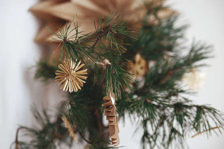 Stylish christmas star straw ornaments and paper angel on pine branches in vase on background sweden star in festive decorated scandinavian room. Eco plastic free decorationsの写真素材