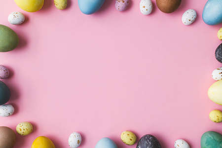 Stylish eggs frame flat lay on pink background. Modern natural dyed colorful easter eggs and...