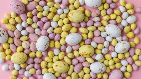 Stylish colorful candy easter eggs flat lay on pink background. Colorful chocolate eggs easter background. Candy banner. Happy Easterの写真素材