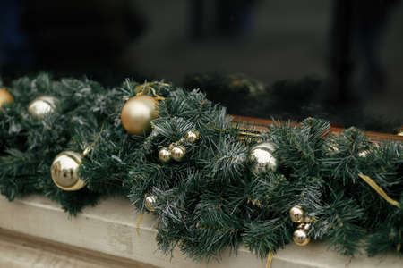 Stylish christmas spruce branches and gold baubles decoration on window of buildings or shop. Christmas festive street decor for winter holidays in european city street. Merry Christmas!の写真素材