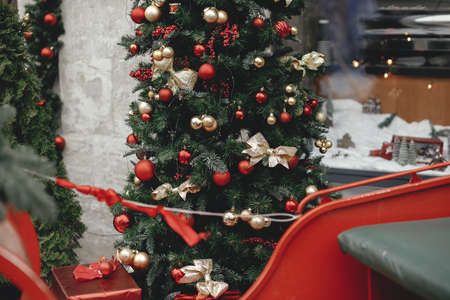 Stylish christmas tree with red and gold baubles and wrapped gift outdoor. Christmas festive street decor for winter holidays in european city street. Merry Christmas!の写真素材