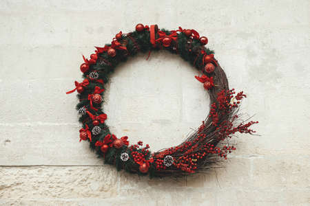 Stylish modern christmas wreath with branches and red baubles on old building wall. Christmas festive street decor for winter holidays in european city street. Merry Christmas!の写真素材