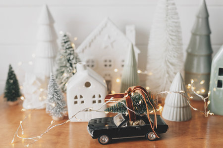 Merry Christmas and Happy New Year! Festive Christmas scene, miniature holiday village. Car with christmas tree, little houses and snowy trees on white background. Styling Christmas sideboardの写真素材