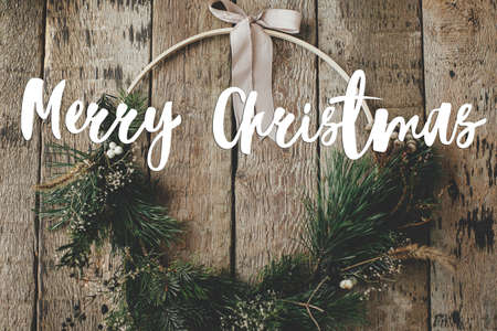 Merry Christmas text on modern boho christmas wreath rustic flat lay. Season's greetings card. Handwritten sign. Happy Holidays!の写真素材