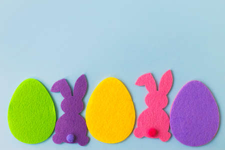 Colorful Easter bunnies and eggs on blue background, top view with space for text. Happy Easter!...