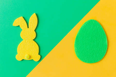 Colorful Easter egg and bunny on green and yellow background, flat lay with space for text. Happy Easter! Green and yellow artificial egg and bunny decor. Creative Easter hunt conceptの写真素材