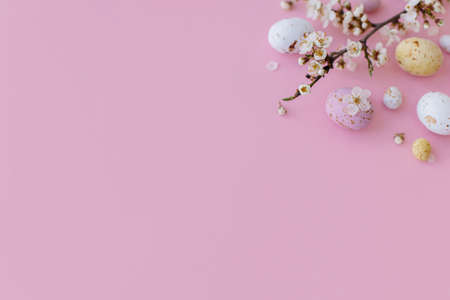 Easter flat lay with space for text. Colorful Easter chocolate eggs and cherry blossoms border on pink background. Happy Easter!. Stylish tender spring banner template. Greeting cardの写真素材