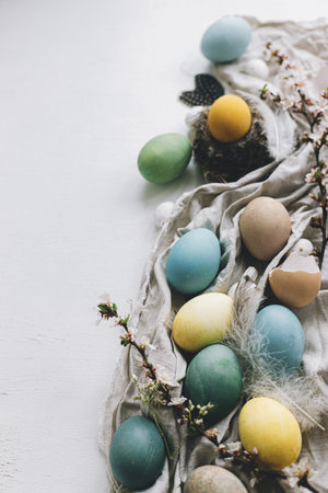 Happy Easter! Stylish rustic Easter flat lay with space for text. Natural dyed colorful eggs, cherry...