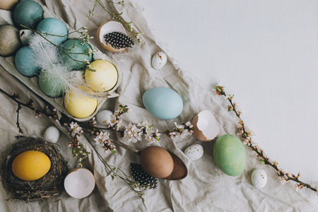 Stylish rustic Easter flat lay. Natural dyed colorful eggs, cherry blossoms, feathers and nest...