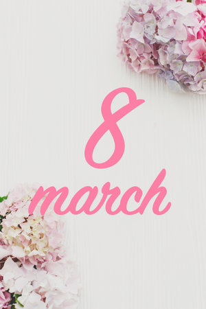 8 march. Happy womens day text on beautiful hydrangea flowers on rustic white wood flat lay. Stylish...