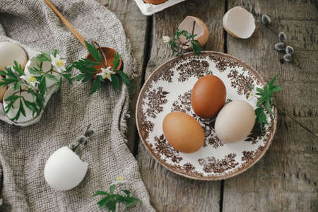 Easter rustic still life. Natural easter eggs, blooming spring flowers, burlap and spoon on rural wooden table. Happy Easter! Simple stylish festive decoration on table.の写真素材