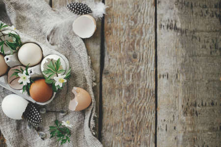 Easter rustic flat lay. Natural easter eggs, blooming spring flowers, feathers, burlap on rural...
