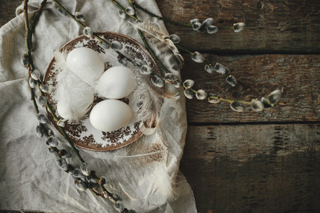Rustic Easter flat lay. Natural egg in nest with feathers, vintage plate,  pussy willow branches and...
