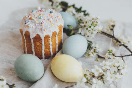 Happy Easter! Stylish easter bread and natural dyed eggs on rustic table with spring blossom and...