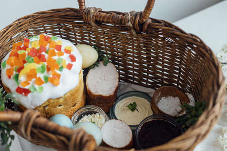 Traditional Easter basket. Natural dyed easter eggs, easter bread, ham, beets, butter, cheese in...