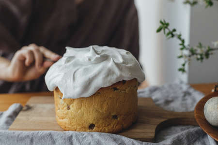Woman decorating homemade easter bread with sugar glaze on rustic table close up. Happy Easter! Woman baking stylish easter cakeの写真素材