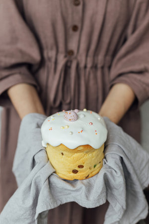 Homemade easter bread in hands on background of rustic room. Happy Easter! Woman holding freshly...