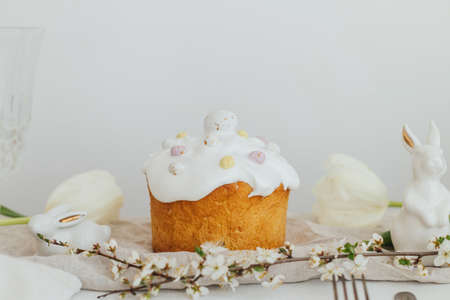 Happy Easter! Homemade easter bread, bunny, white tulips on rustic table in room. Modern easter...