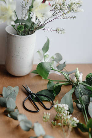 Beautiful fresh flowers and scissors on wooden background, floral arrangement. Stylish bouquet in ceramic vase on wooden windowsill. Spring modern bouquetの写真素材