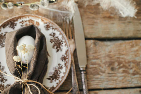Rustic Easter table setting top view. Natural egg in napkin with flowers, setting  with vintage...