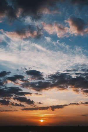 Beautiful sunset. Red sun and clouds on orange and blue sky. Amazing sunset or sunrise wallpaper. Breathtaking sceneryの写真素材