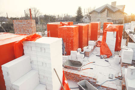 Building materials at construction site. Autoclaved aerated blocks on concrete foundation, process...