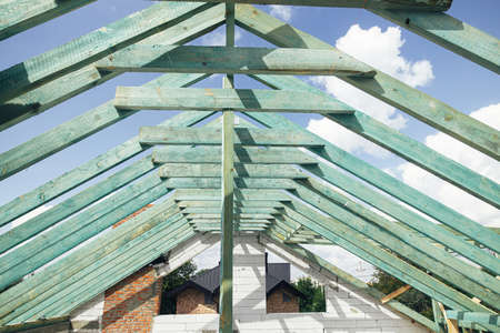 Wooden roof framing. Unfinished roof trusses and aerated concrete block walls, view in attic with...