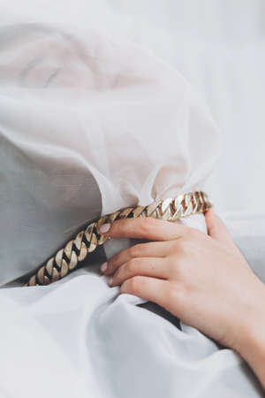 Social isolation and pressure. Sensual woman under veil posing with golden necklace in room. Portrait of young female covered with light fabric and hand on neck. Self care concept. Suffocateの写真素材