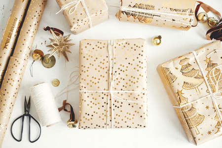Stylish christmas gift flat lay. Modern wrapped christmas gift boxes, festive paper, golden...