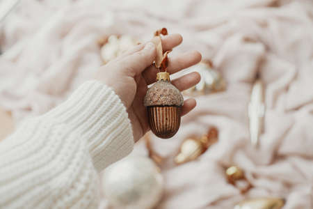Hand holding christmas vintage ornament on background of soft pastel cloth with stylish baubles....