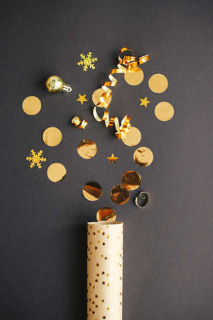 Merry Christmas and Happy New Year! Modern golden confetti popping from festive wrapping paper on...