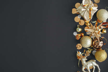 Modern christmas flat lay with golden baubles, confetti and decorations on black background. Seasons greeting card template with space for text. Stylish holiday banner. Merry Christmas!の写真素材