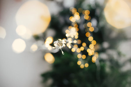 Merry Christmas and Happy New Year! Stylish christmas lights close up on moody background. Warm golden illumination bokeh and garland light close up. Atmospheric winter time, holiday decorの写真素材
