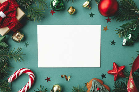 Christmas card mock up. Modern greeting card flat lay with stylish christmas decorations and fir branches on green background. Empty postcard template with space for text. Merry Christmas!の写真素材