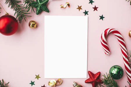 Christmas card flat lay. Modern greeting card mock up and red christmas decorations and ornaments on...