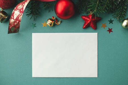 Christmas card mock up. Modern greeting card flat lay with stylish christmas decorations and fir branches on green background. Empty postcard template, space for text. Happy Holidays!の写真素材