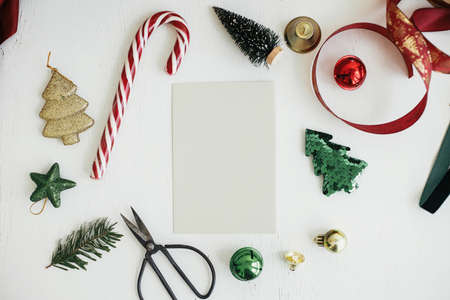 Christmas card mock up. Empty greeting card flat lay with christmas stylish decorations, ribbons, ornaments on white rustic table. Postcard template with space for text. Happy Holidays!の写真素材