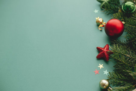 Modern Christmas banner. Stylish christmas border with festive decorations, confetti, fir branches on green background. Merry Christmas!  Seasons greetings card template, space for textの写真素材