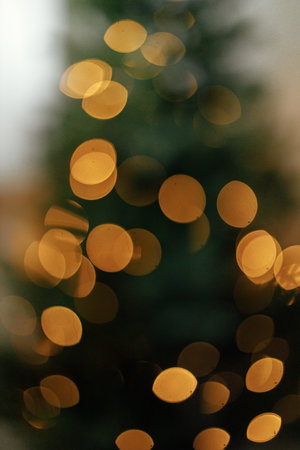 Blurry illuminated christmas tree. Abstract blurred christmas tree with golden lights in evening...