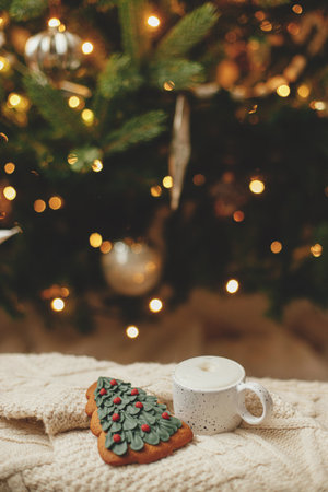 Atmospheric winter hygge. Warm cup of coffee and christmas tree gingerbread cookie on knitted...