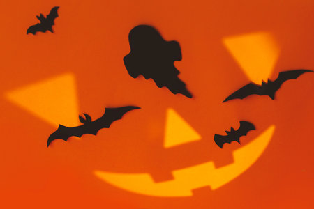 Spooky Halloween. Black ghosts and bats decorations with jack o lantern face on orange background. Happy Halloween! Trick or treat! space for textの写真素材