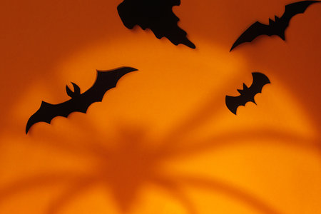 Spooky Halloween. Black ghosts and bats decorations with spider's shadow on orange background. Happy Halloween! Trick or treat! space for textの写真素材