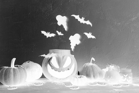 Happy Halloween! Spooky Jack o lantern candy bucket, pumpkins, black spiders, bats, ghosts decorations on dark night background. Creative evil Halloween template with space for textの写真素材