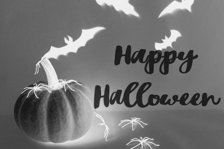 Happy Halloween text on spooky black spiders, pumpkin, ghosts, bats decorations in dark. Happy Halloween! Creative greeting card, handwritten sign. Trick or treat!の写真素材