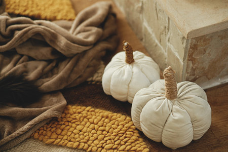 Cute handmade textile pumpkins on cozy rug at fireplace. Stylish autumn decor at warm fireplace in rustic farmhouseの写真素材
