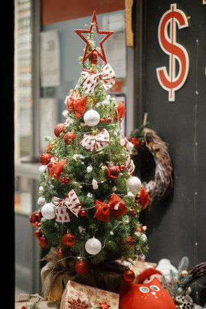 Stylish christmas tree with ornaments and currency exchange signs in store showcase in evening. Modern christmas decor in city street. Winter holidays in Europeの写真素材
