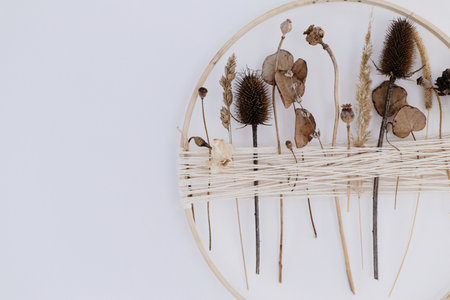 Stylish boho autumn wreath with dry flowers. Wooden hoop, thread and dry herbs wreath hanging on...